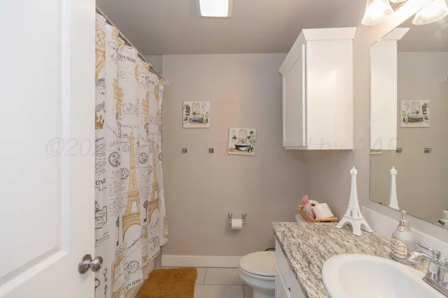a bathroom with a granite countertop toilet sink and mirror