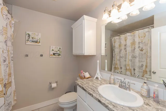 a bathroom with a granite countertop sink a toilet and a mirror