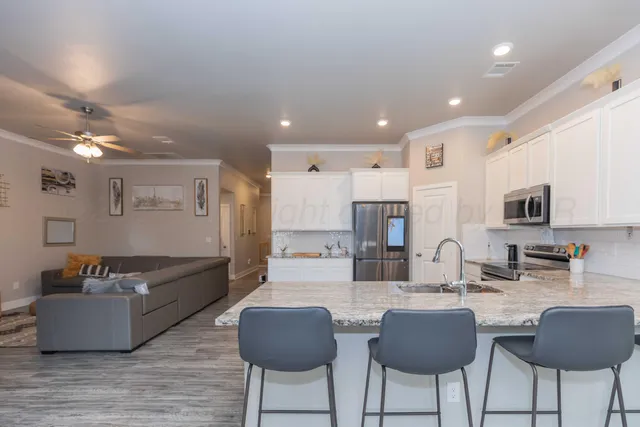 a kitchen with stainless steel appliances kitchen island granite countertop a sink and chairs