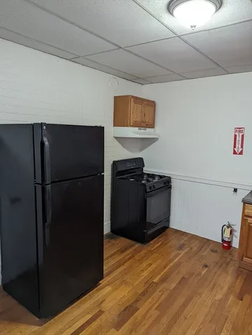 a kitchen with a refrigerator and a wooden floor
