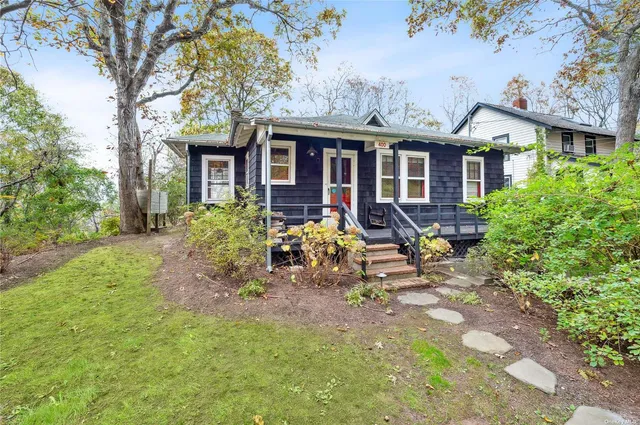 a front view of house with yard outdoor seating and trees in the background
