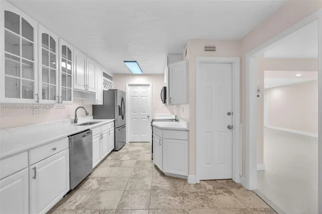 a large white kitchen with cabinets and stainless steel appliances