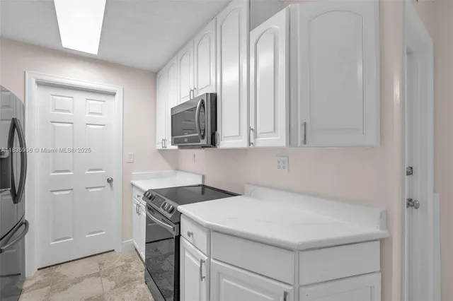 a kitchen with white cabinets and stainless steel appliances
