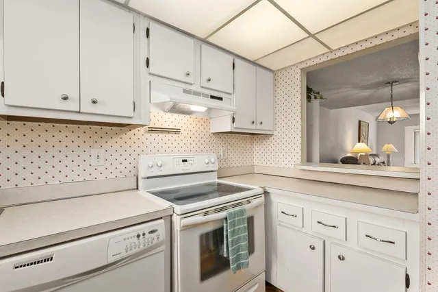 a kitchen with granite countertop white cabinets and white appliances