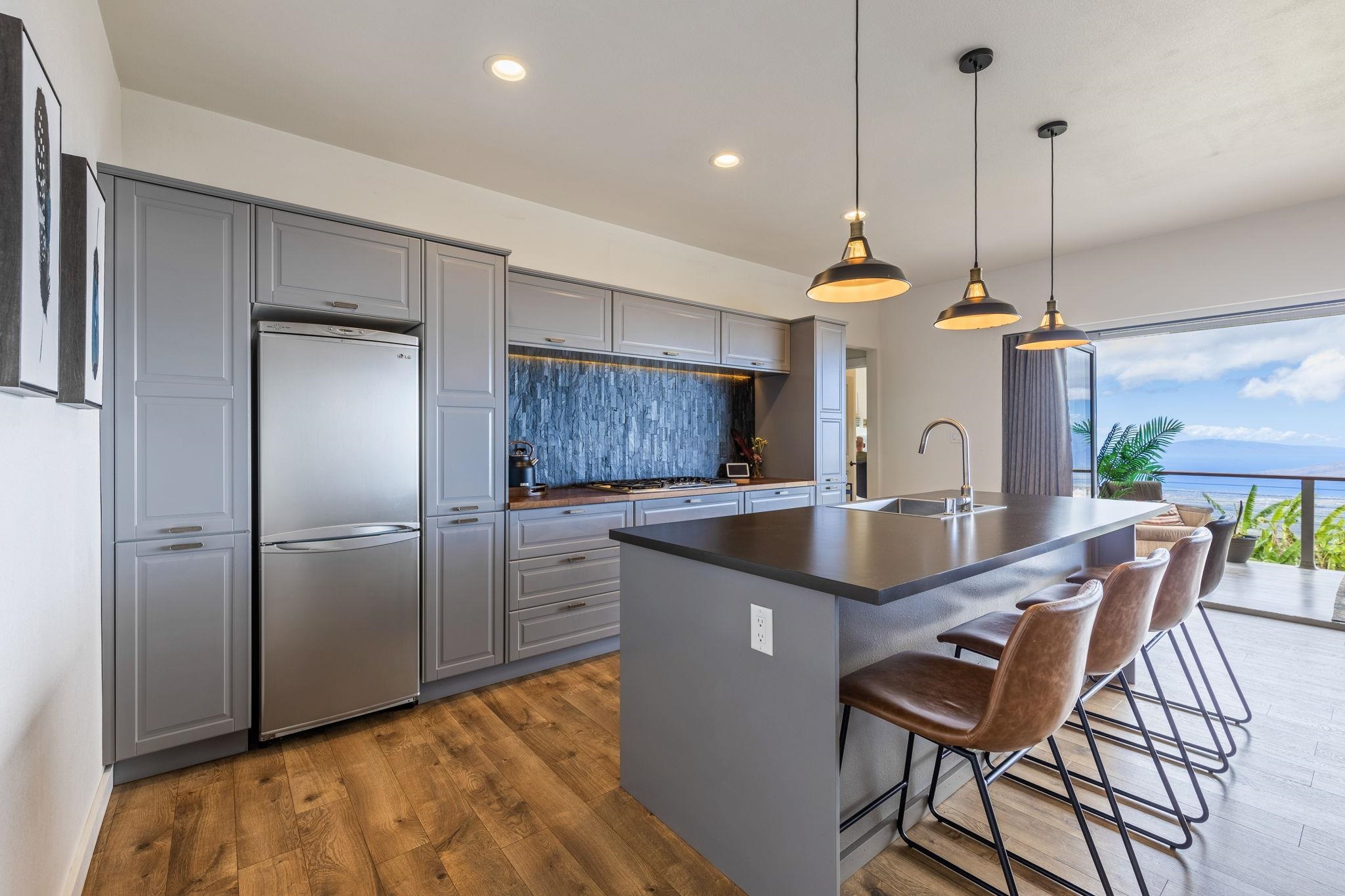 59 Waipoli Road Kula, HI 96790 - Photo 10 of 47 a kitchen with stainless steel appliances granite countertop a kitchen island a refrigerator and a view of living room