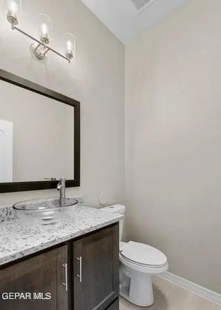 a bathroom with a granite countertop sink a toilet and a mirror