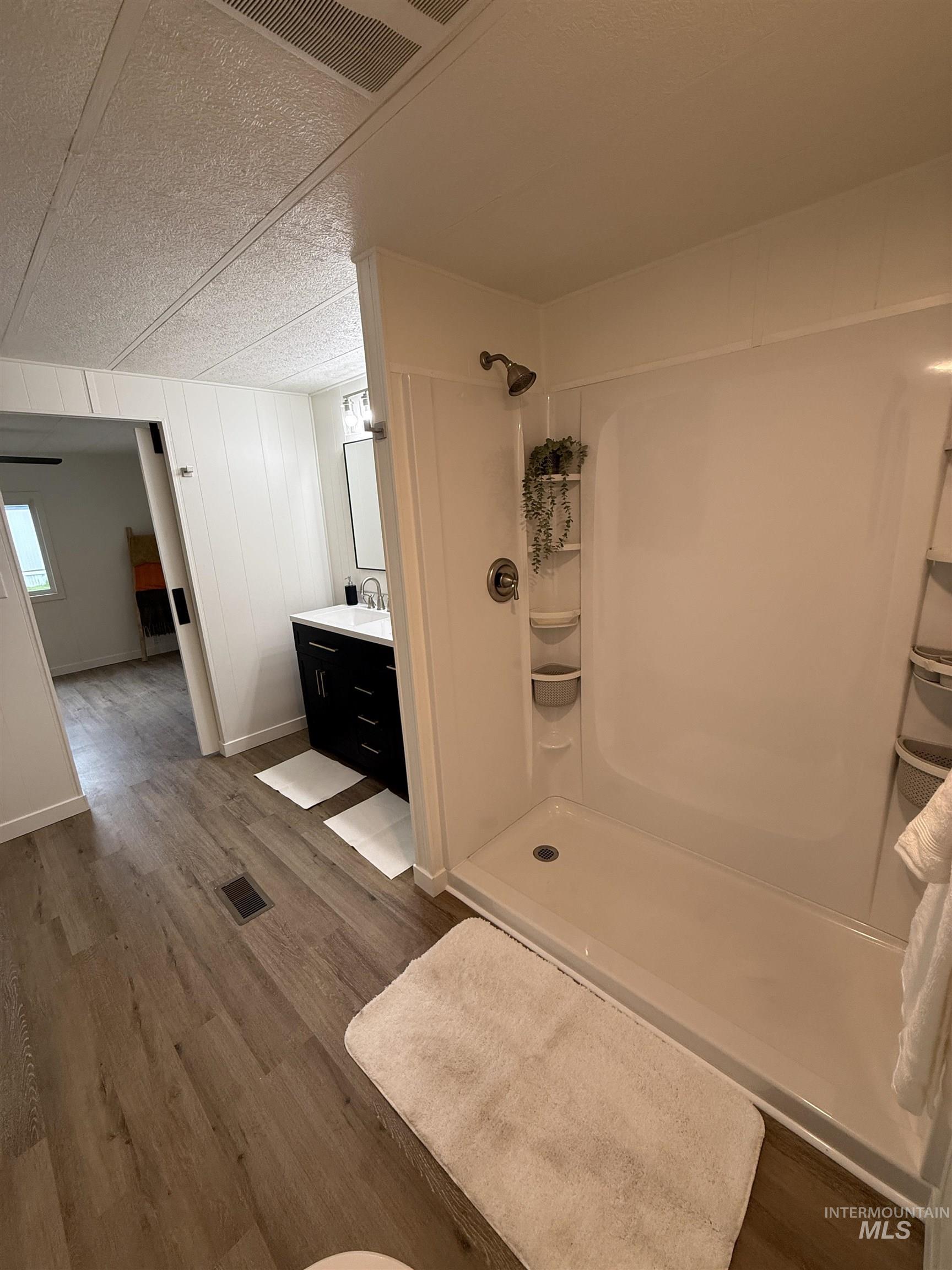424 West Cherry Lane, Unit 5 Meridian, ID 83642 - Photo 18 of 27 Bathroom with a shower stall, vanity, dark wood-style flooring, and a textured ceiling