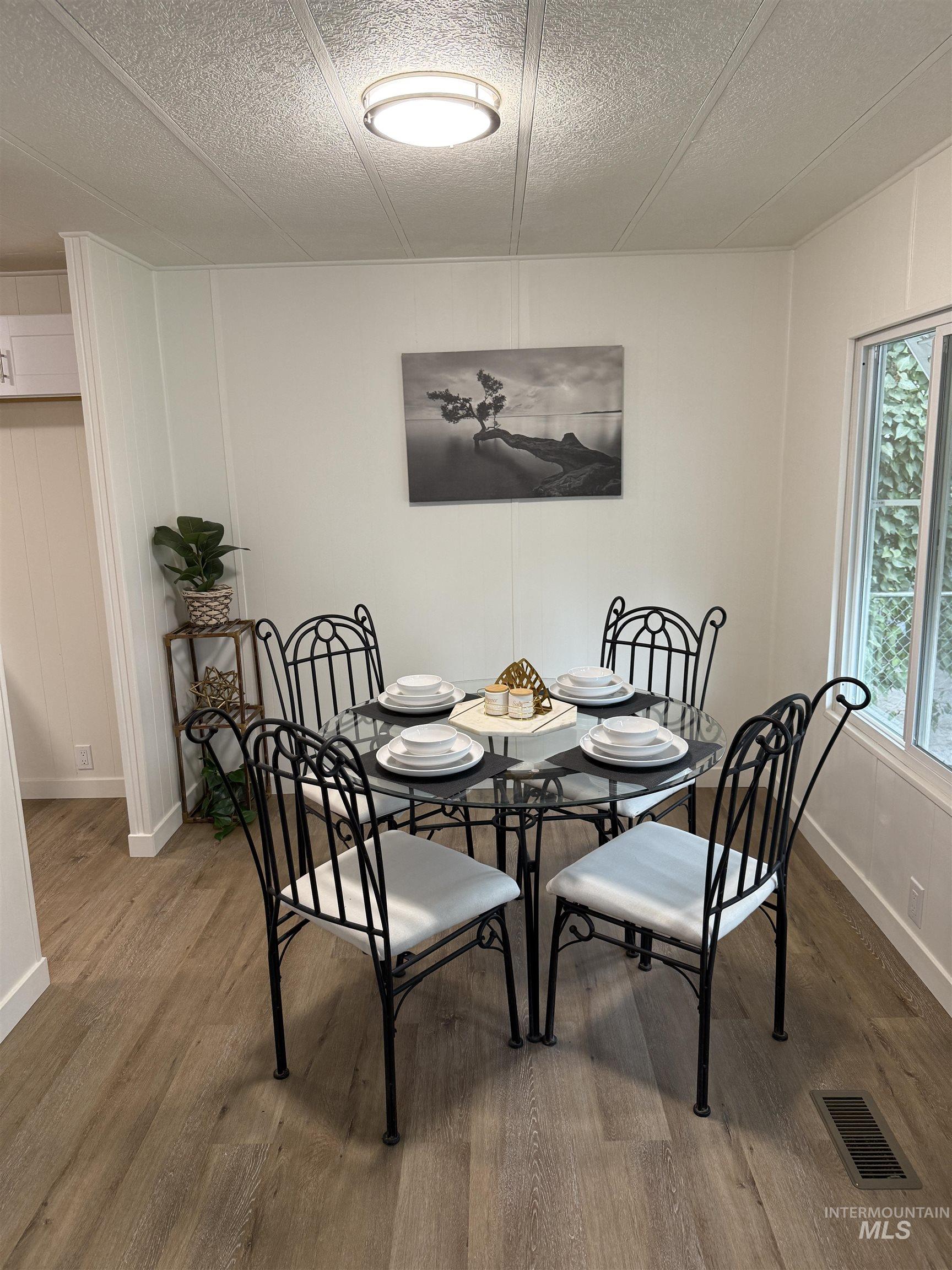 424 West Cherry Lane, Unit 5 Meridian, ID 83642 - Photo 8 of 27 Dining space featuring wood finished floors, a decorative wall, and a textured ceiling
