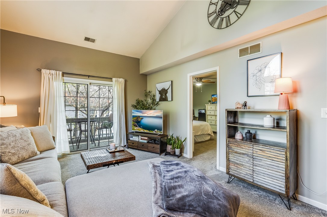 Living area with high vaulted ceiling, ceiling fan, carpet floors, and visible vents
