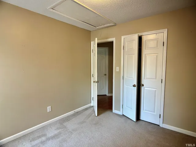 a view of an empty room with closet and a window