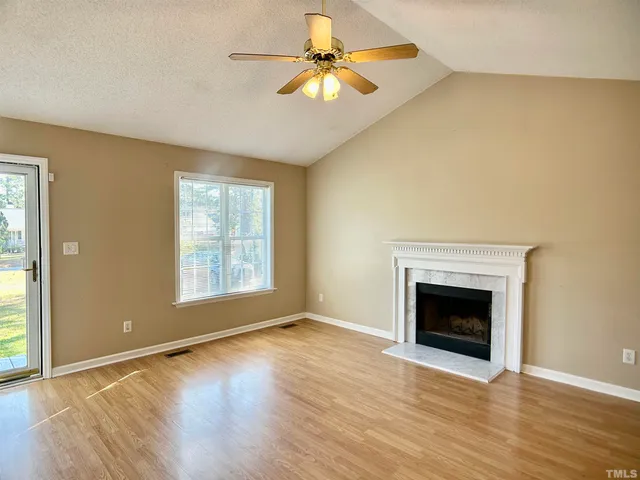 an empty room with chandelier fan and windows