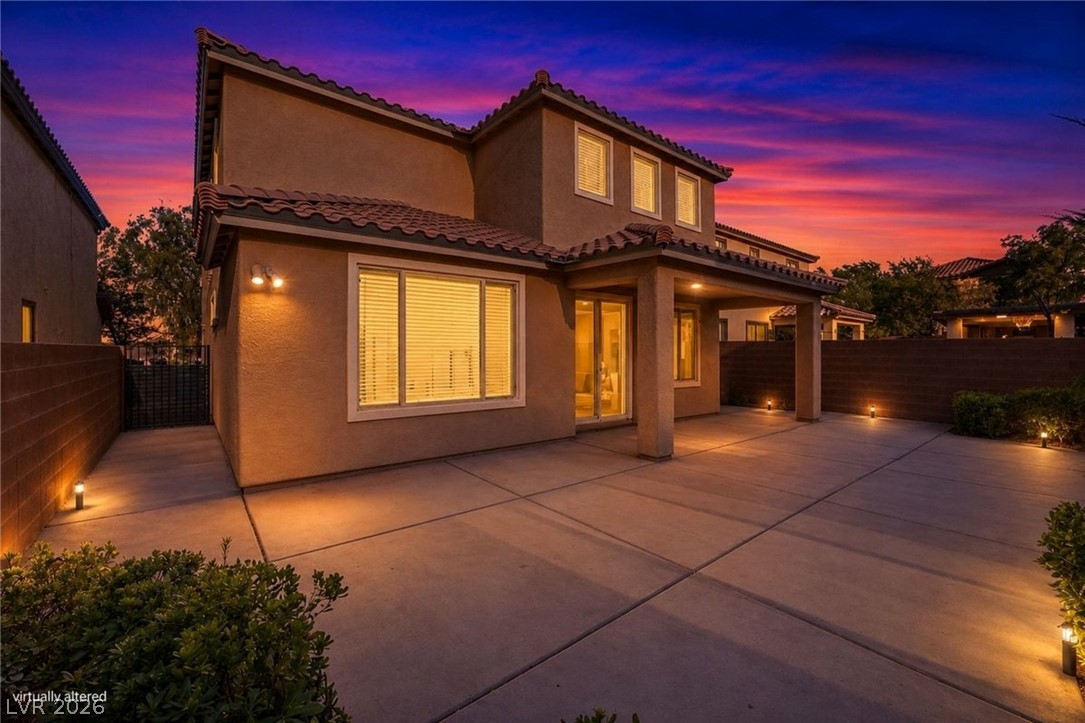 11009 Prairie Grove Road Las Vegas, NV 89179 - Photo 6 of 49 A spacious backyard patio with covered sections, perfect for evening gatherings under a vibrant sunset sky.