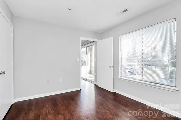 a view of an empty room with a window and wooden floor