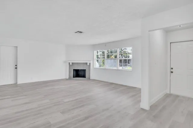 a view of an empty room with a window and fireplace