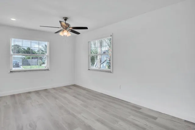 a view of empty room with wooden floor and fan