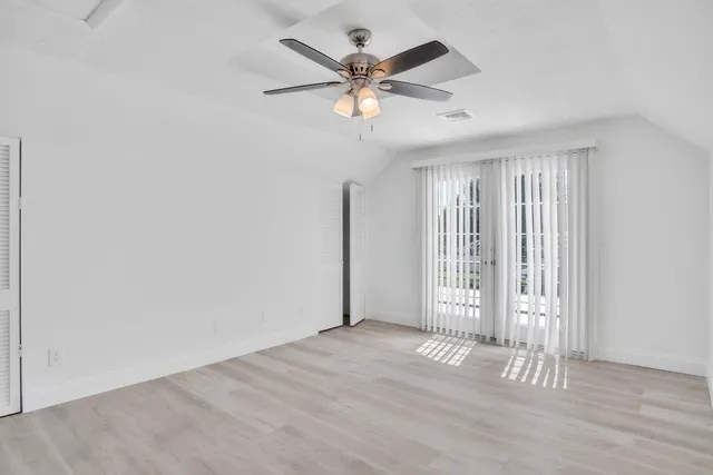 an empty room with wooden floor and ceiling fan