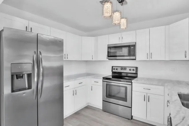 a kitchen with a refrigerator stove and white cabinets