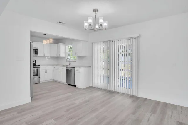 a view of a kitchen with a sink a chandelier and windows