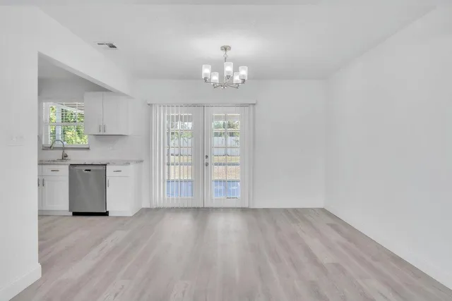an empty room with wooden floor cabinet and windows