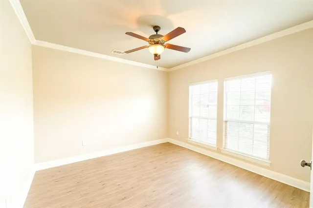 an empty room with wooden floor fan and windows
