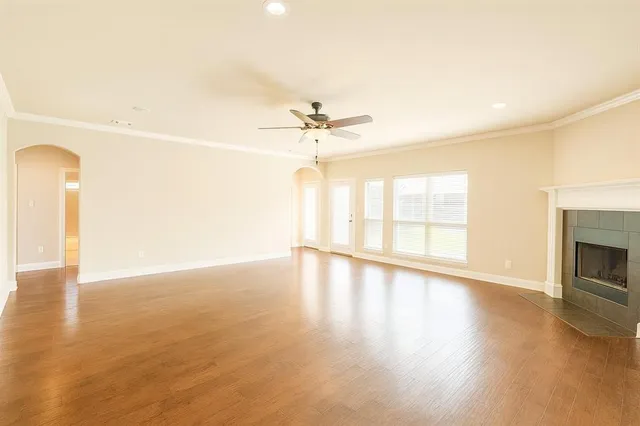 an empty room with wooden floor fireplace and windows