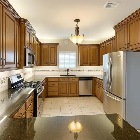 a kitchen with stainless steel appliances granite countertop a stove a sink dishwasher a refrigerator and cabinets with wooden floor