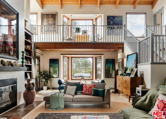 a living room with furniture a fireplace and a floor to ceiling windows