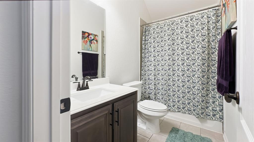 5216 Troupe Road McKinney, TX 75071 - Photo 36 of 40 Bathroom featuring a dark wood-finish vanity with a white countertop and integrated sink, a matching mirror, a toilet, and a shower-over-tub combination with a patterned curtain