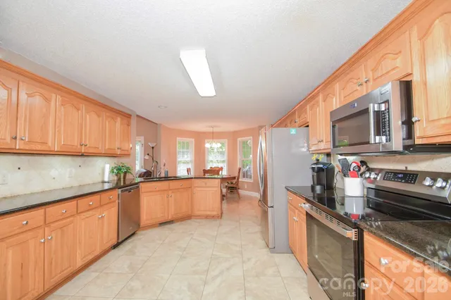 a kitchen with stainless steel appliances granite countertop a refrigerator a stove and a sink