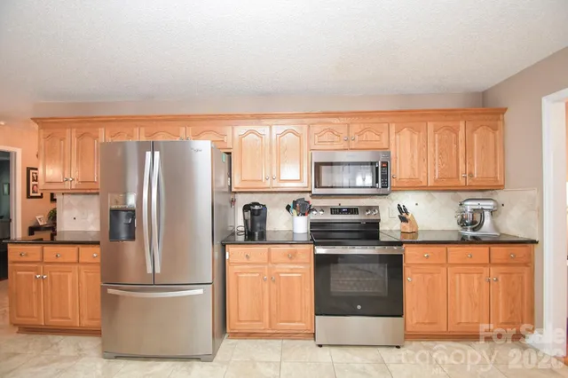 a kitchen with stainless steel appliances granite countertop a sink and a refrigerator