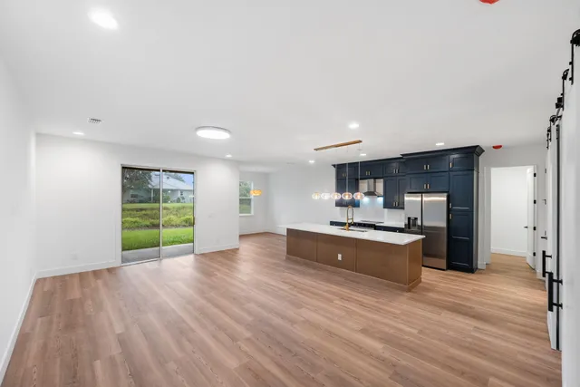 a living room with stainless steel appliances kitchen island hardwood floor and window
