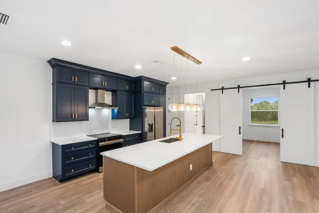 a living room with stainless steel appliances kitchen island a stove and a refrigerator