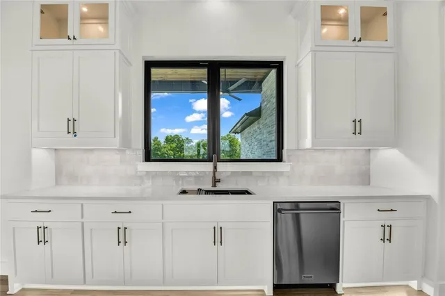 a kitchen with white cabinets and a window