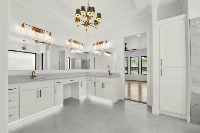 a large white kitchen with a white kitchen island a sink stainless steel appliances and cabinets
