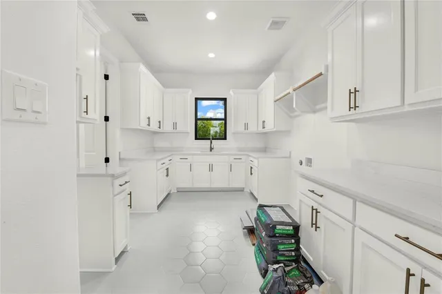 a kitchen with white cabinets and window