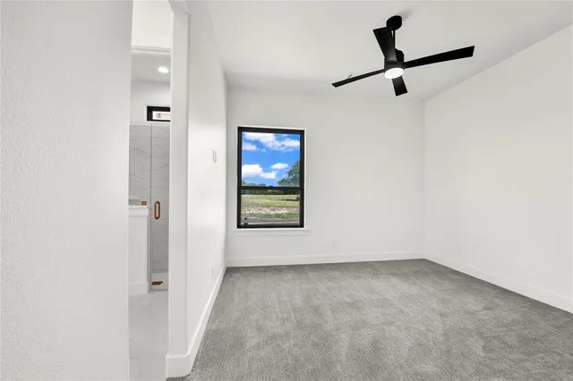 an empty room with a window and a ceiling fan