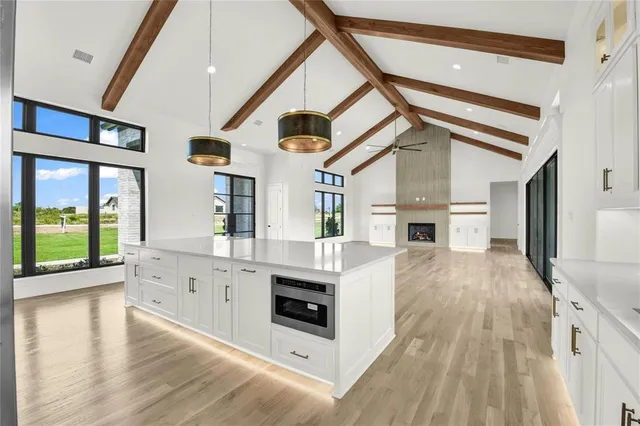 a kitchen with stainless steel appliances kitchen island granite countertop a stove and a white cabinets with wooden floor