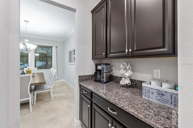 a kitchen with granite countertop a coffee maker on granite counter tops and white cabinets