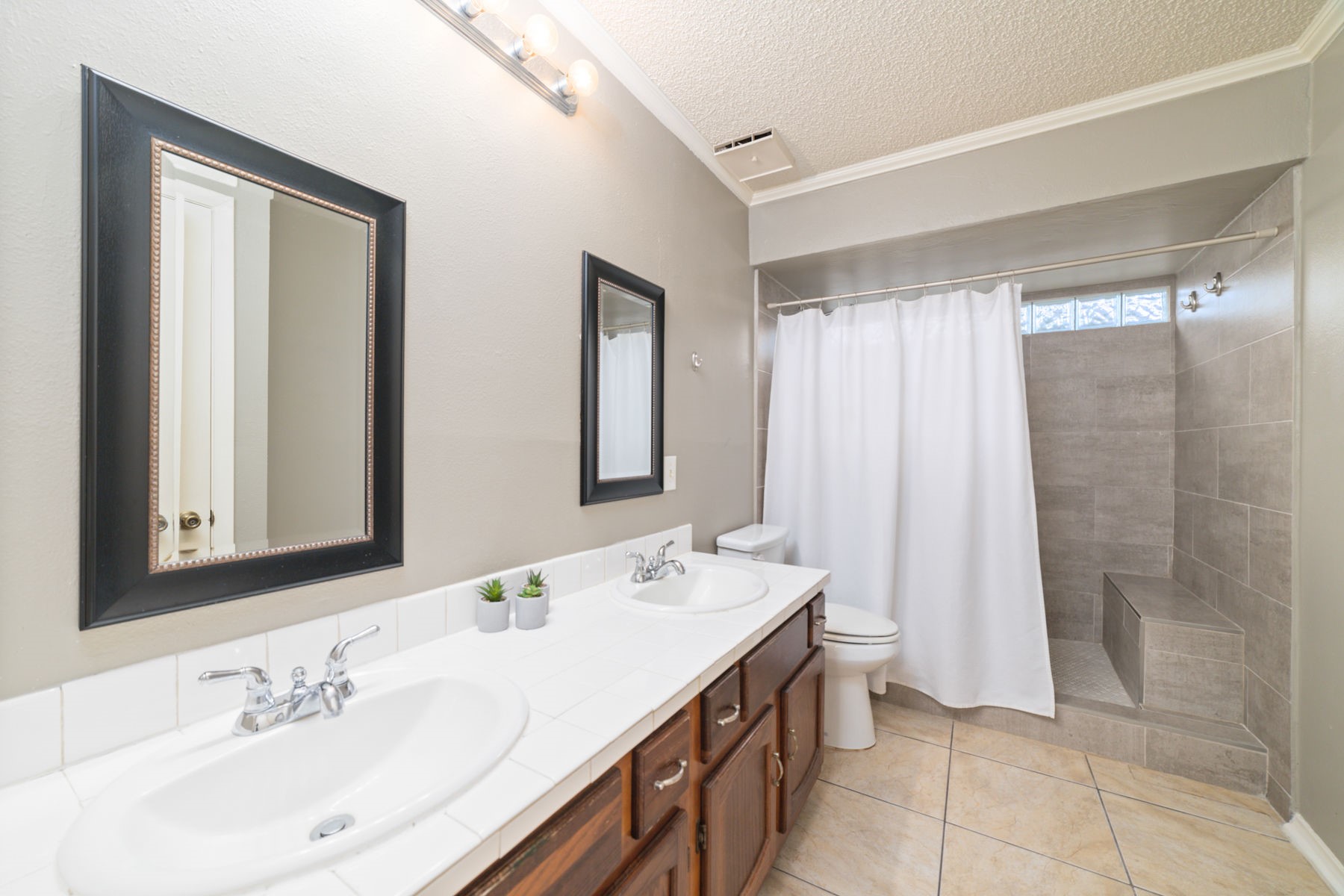 25402 Mill Pond Lane Spring, TX 77373 - Photo 14 of 24 This bathroom features a modern design with dual sinks, stylish framed mirrors, and a spacious tiled shower with a bench. The neutral color palette and ample lighting create a bright and inviting space.