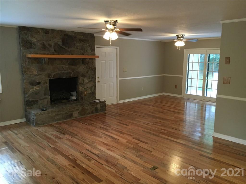 21 Sitton Road Sylva, NC 28779 - Photo 6 of 16 a view of an empty room with wooden floor fireplace and a window