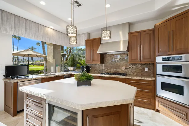 a kitchen with stainless steel appliances granite countertop a sink a stove and a wooden floors