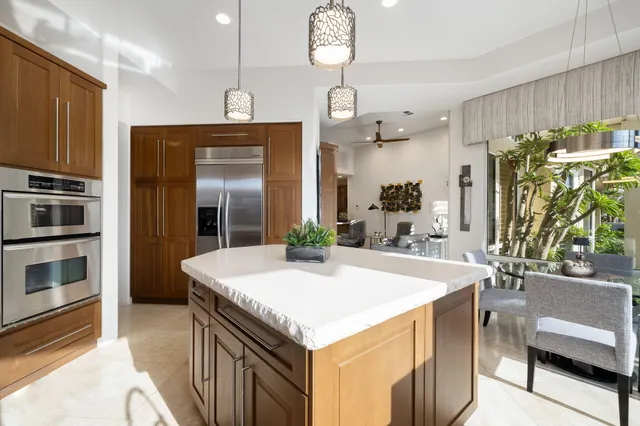 a kitchen with stainless steel appliances kitchen island granite countertop a refrigerator a oven a sink and a dining table with wooden floor