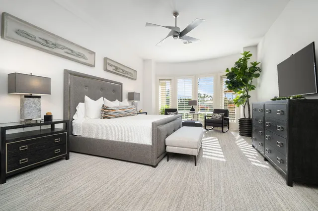 a bedroom with a large bed and a flat tv screen on dresser