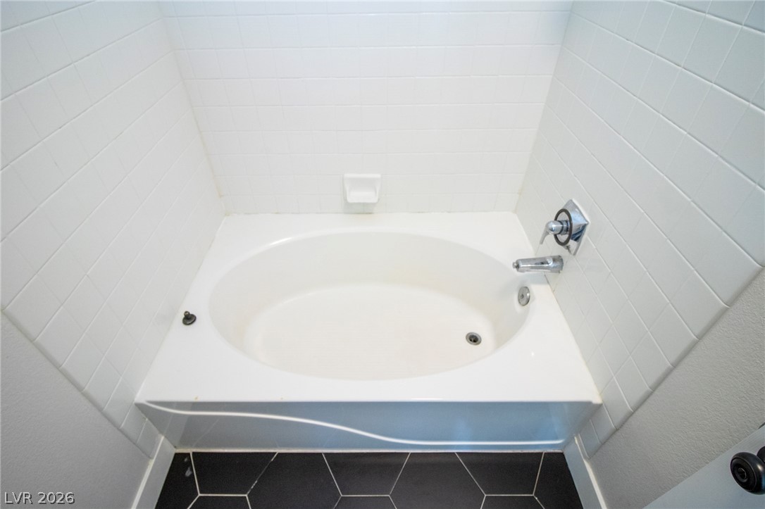 1468 Reef Ridge Court Las Vegas, NV 89128 - Photo 21 of 22 A deep soaking tub with clean white tile surround offers a peaceful retreat.