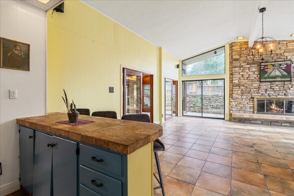 209 Finn Street Austin, TX 78734 - Photo 11 of 40 Kitchen with a textured ceiling, a peninsula, tile patterned floors, a kitchen breakfast bar, and a notable chandelier
