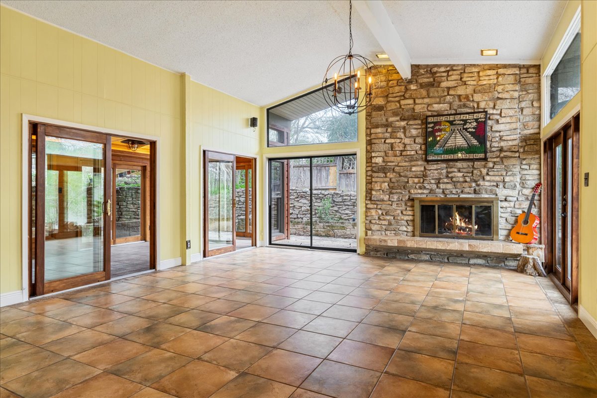 209 Finn Street Austin, TX 78734 - Photo 5 of 40 View from entry of the living room with chandelier, fireplace, tile flooring, and beamed ceiling