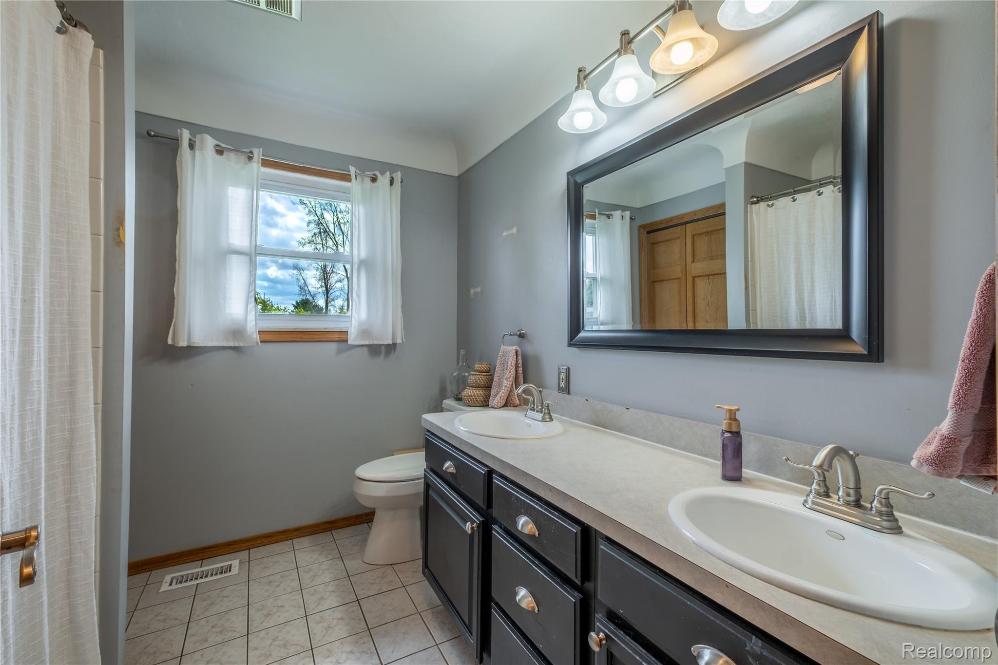 11430 Silver Lake Road Byron, MI 48418 - Photo 16 of 32 Full bathroom featuring a shower with curtain, double vanity, and light tile patterned flooring