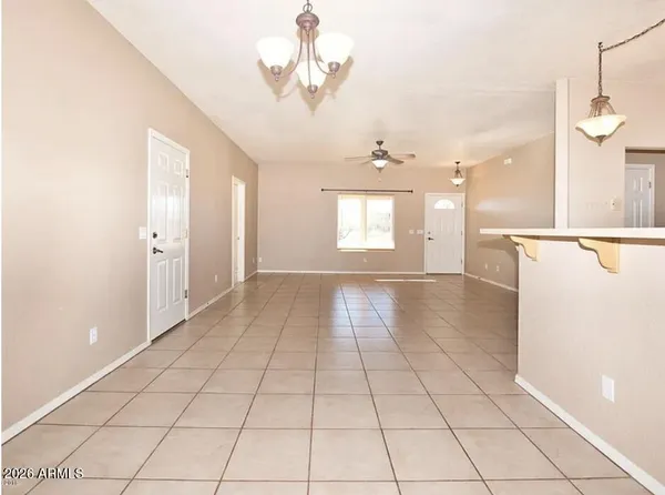 a view of an empty room and window a kitchen and chandelier fan