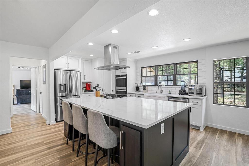 a large kitchen with kitchen island a dining table and stainless steel appliances