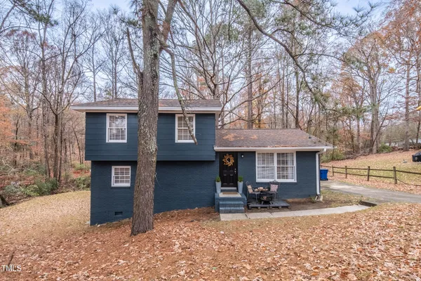 a view of a house with a yard and large tree